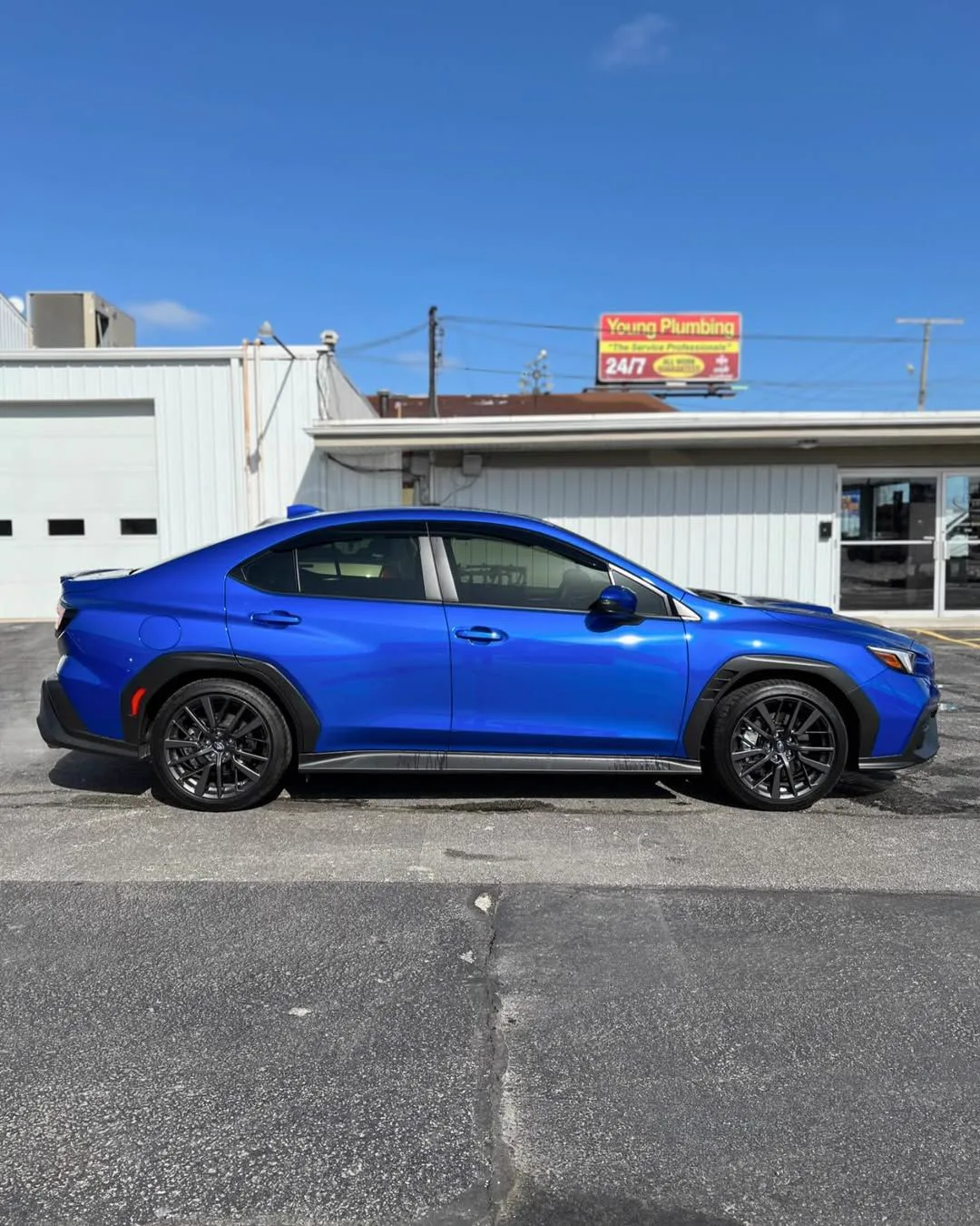 Blue Subaru car parked in front of a building on a sunny day.